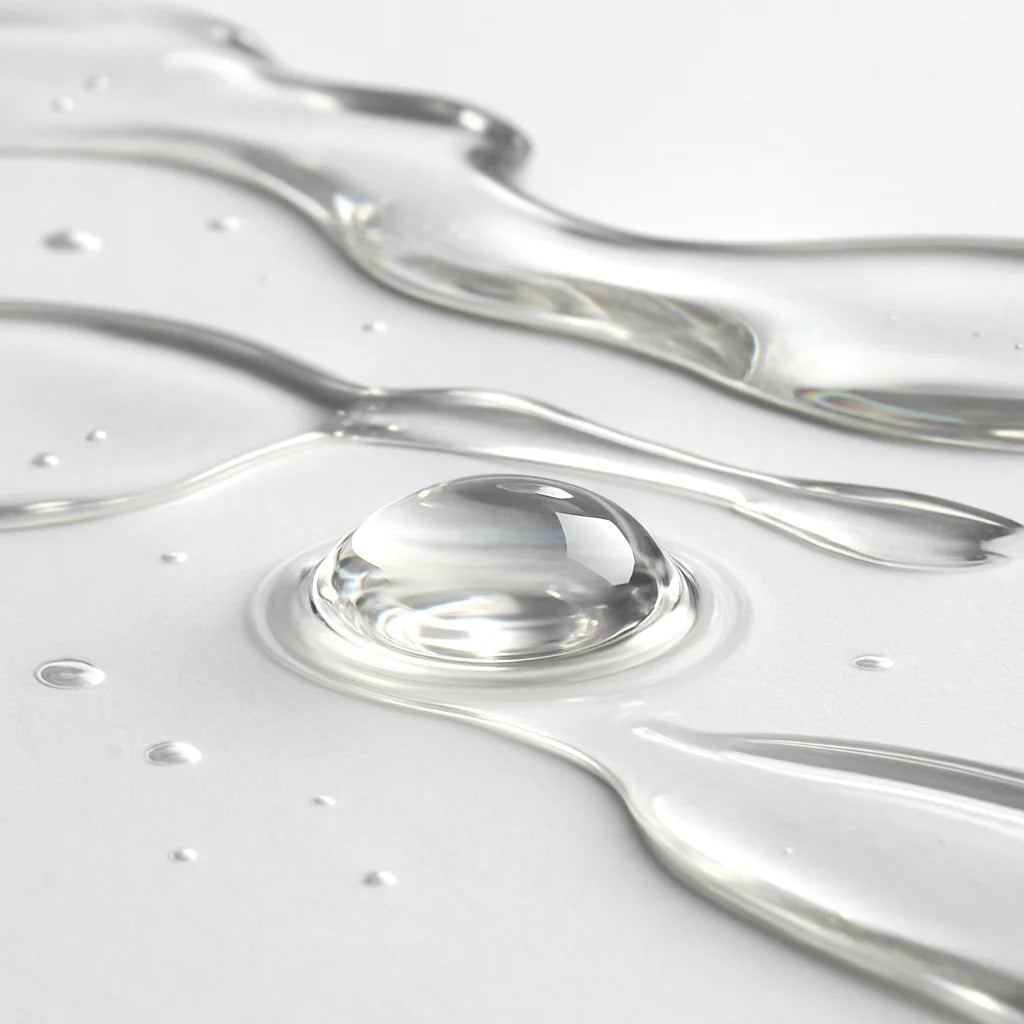 Close-up of water droplets and flowing water on a light gray background