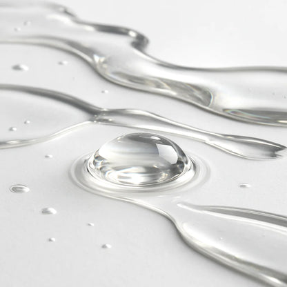 Close-up of water droplets and flowing water on a light gray background