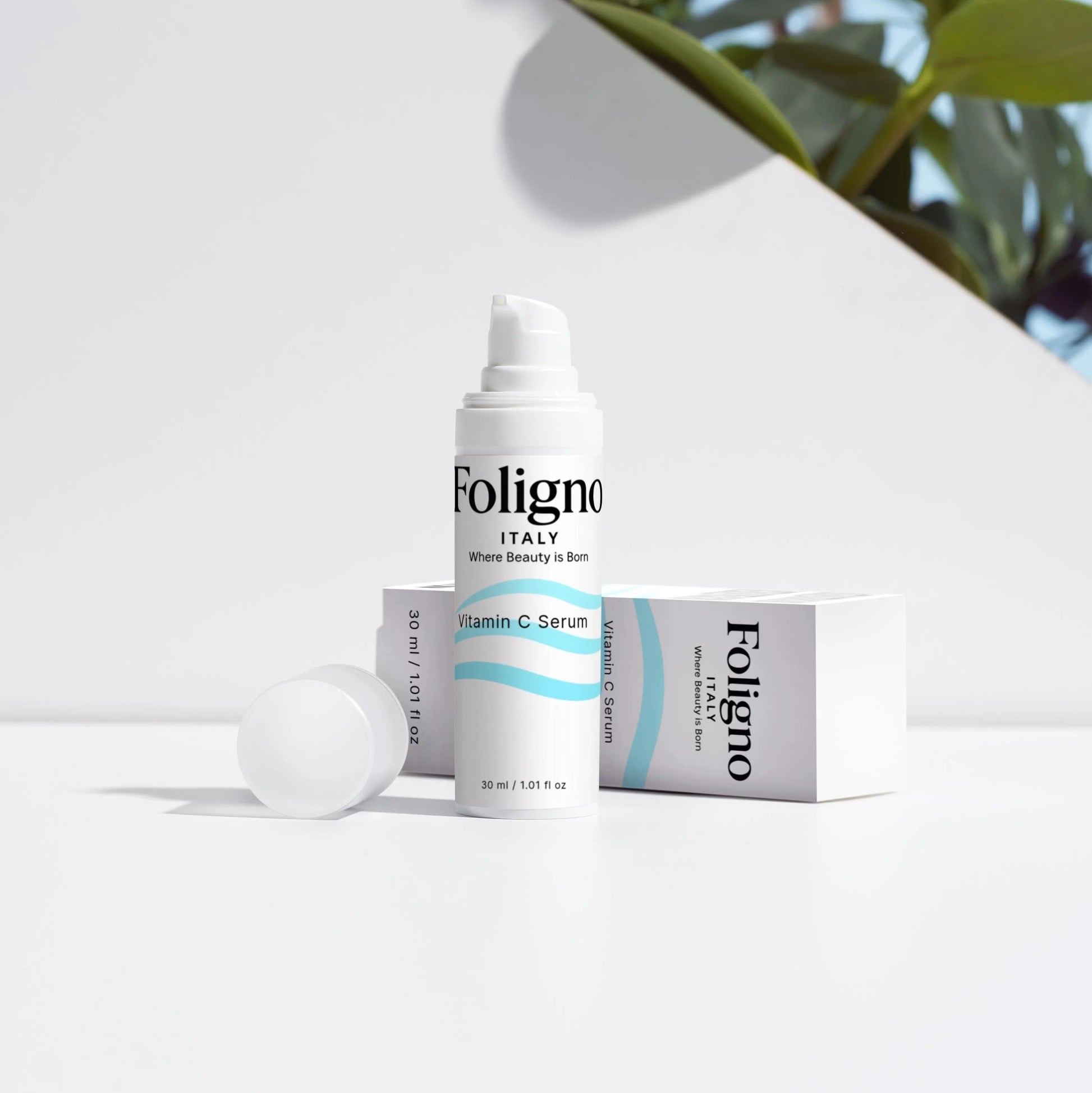 Foligno skincare products on a white surface with green leaves in the background