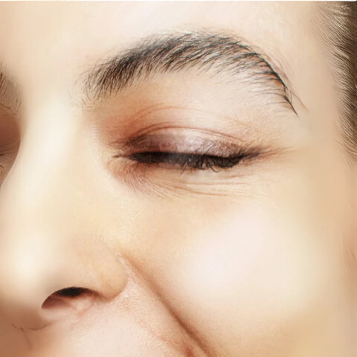 Close-up of a person's eye with a focus on the eyelid and eyebrow area.