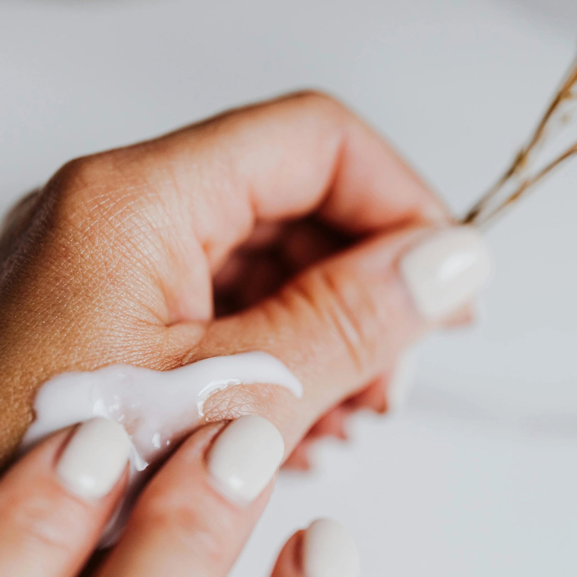 Close-up of a hand applying cream to another hand with a blurred background