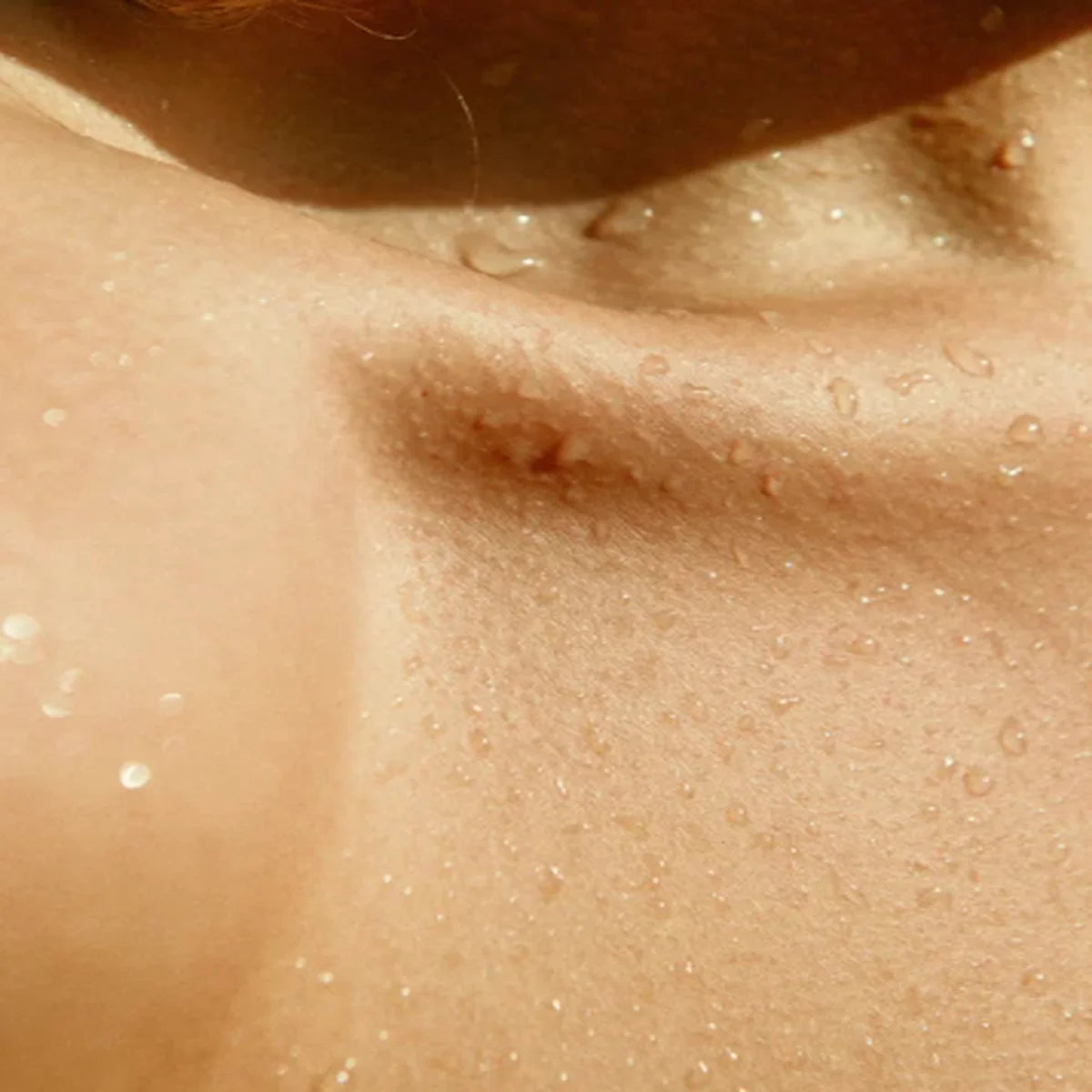 Close-up of a person's shoulder with water droplets on skin